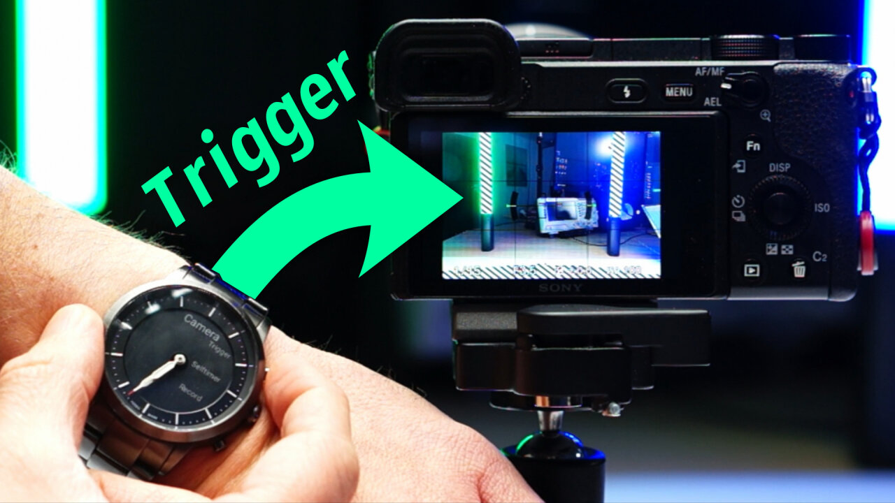 Thumbnail of the youtube video: The image shows a camera in front of cyan and green lights with its display on. In front of this is a smartwatch from which an arrow points to the camera. The arrow is labeled with the word Trigger